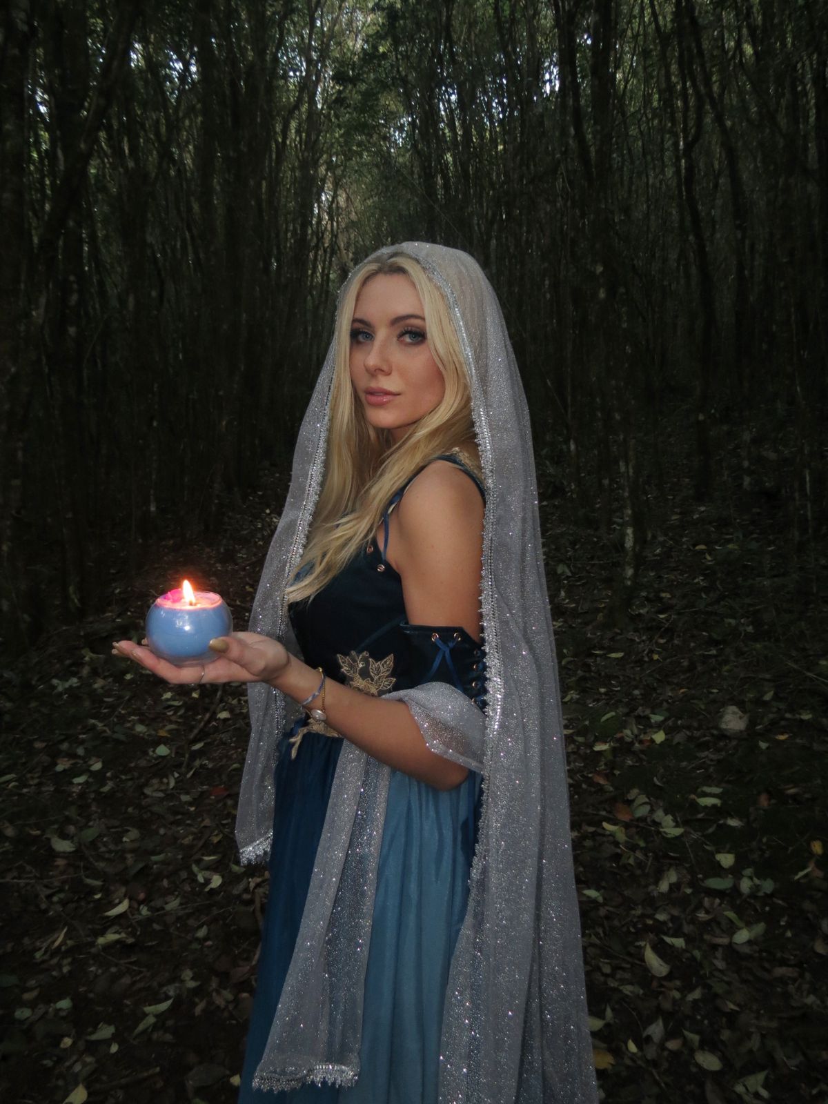 Mãos segurando vela com ervas secas